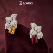Blazing Petals Earrings Gross wt – 16.71 gms Gold Wt – 13.15 gms Diamonds – 2.36 cts Ruby wt – 9.74 cts Yellow Citrine wt – 5.72 cts These earrings are inspired by the fiery petals of an exotic bloom. The vibrant rubies and diamonds are arranged in a floral pattern, capturing the essence of nature’s fierce beauty. Ideal for those who wish to make a bold and striking impression.